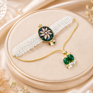 Handmade pearl beaded rakhi featuring a green floral centerpiece with kundan stones, gold detailing and traditional Indian craftsmanship.